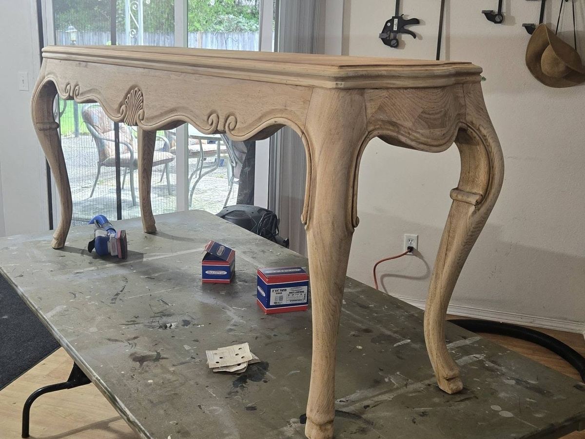 Carved console table before restoration on a studio work surface