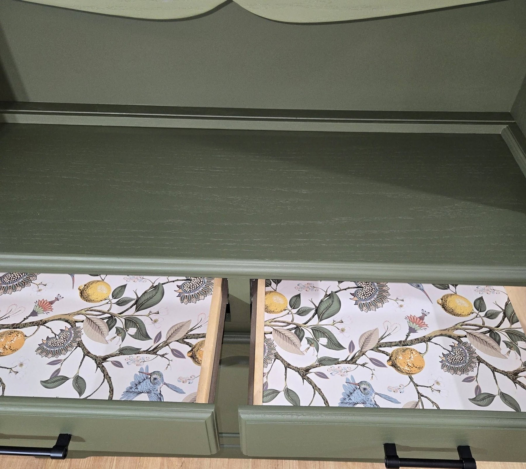 Drawer interior detail in restored muted sage hutch with botanical patterned liners and black pulls