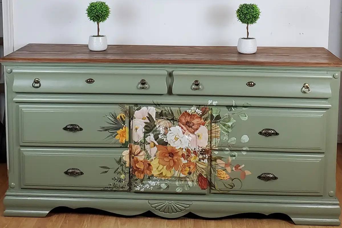 Sage green long dresser after restoration with floral center artwork and warm wood top